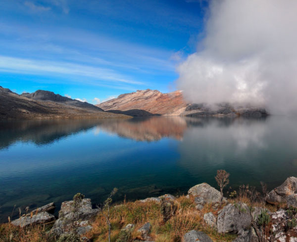 Paisaje serrano con un lago rodeado de rocas y vegetación.