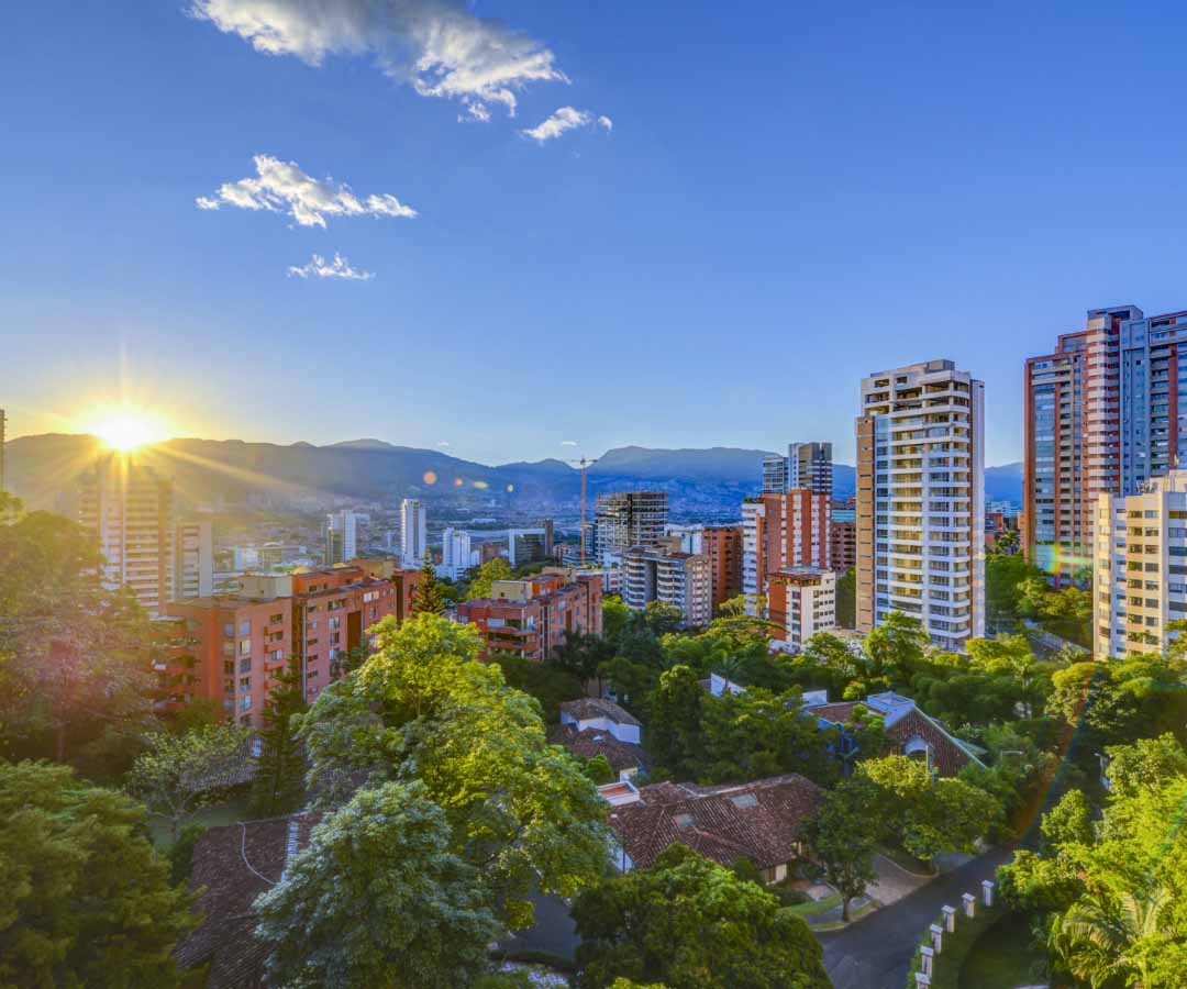 Vista panorámica de Medellín, Antioquia, al amanecer, con edificios modernos rodeados de montañas.