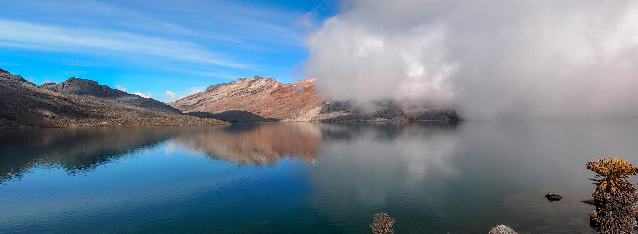 Paisaje serrano con un lago rodeado de rocas y vegetación.