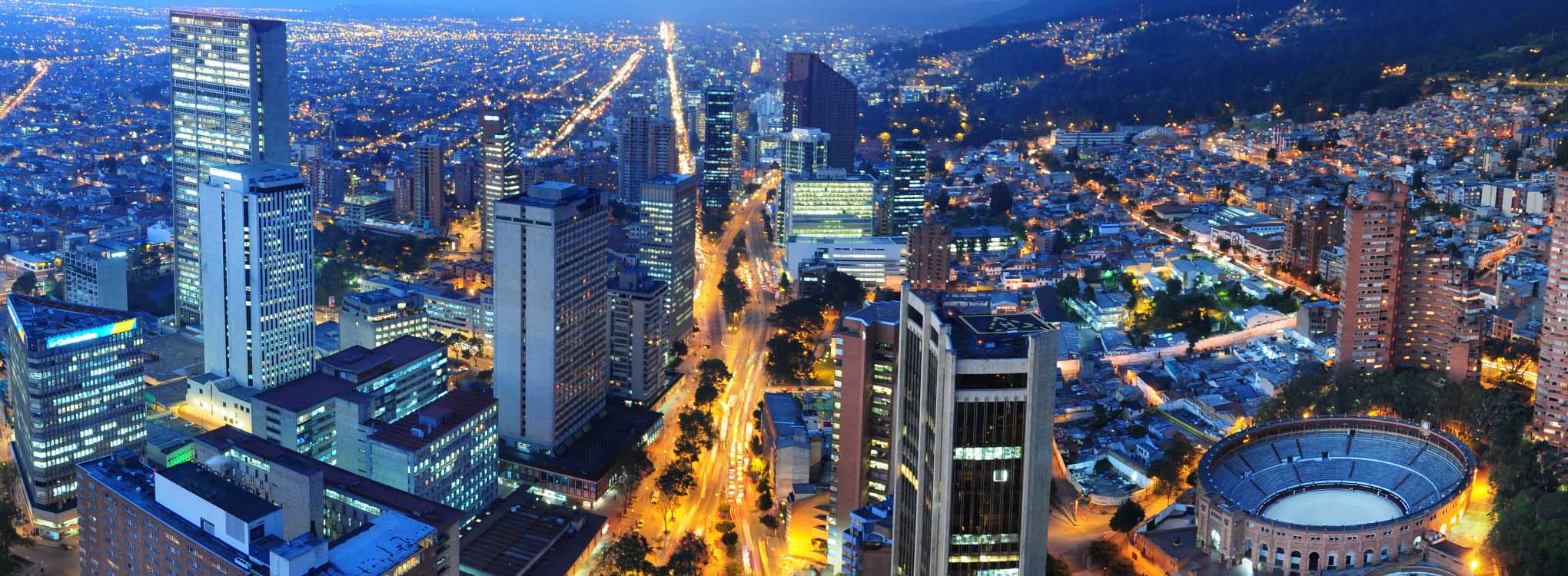 Vista nocturna de Bogotá, destacando sus modernas edificaciones, avenidas iluminadas.