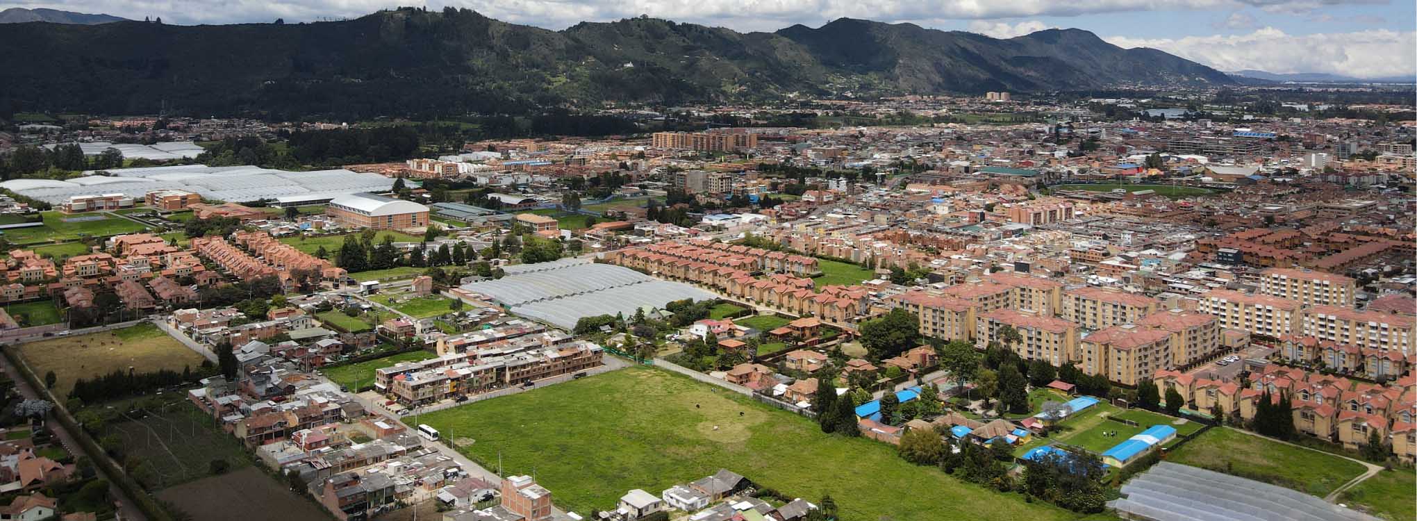 ista aérea de una ciudad en Cundinamarca, rodeada de montañas y cielos despejados.