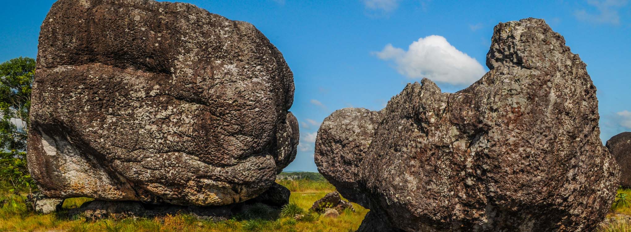 Formaciones rocosas imponentes en un paisaje abierto con una estatua en la cima de una de las rocas.