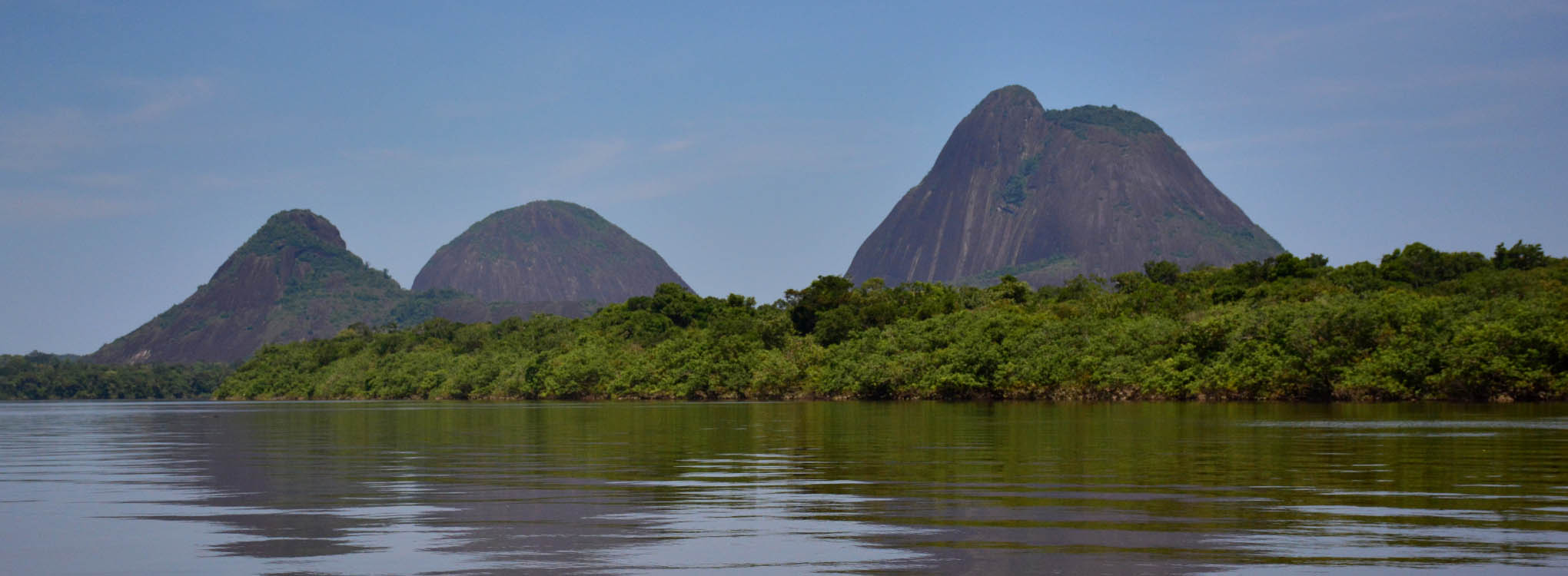 Paisaje de los Cerros de Mavecure reflejados en el río Inírida, rodeados de vegetación.