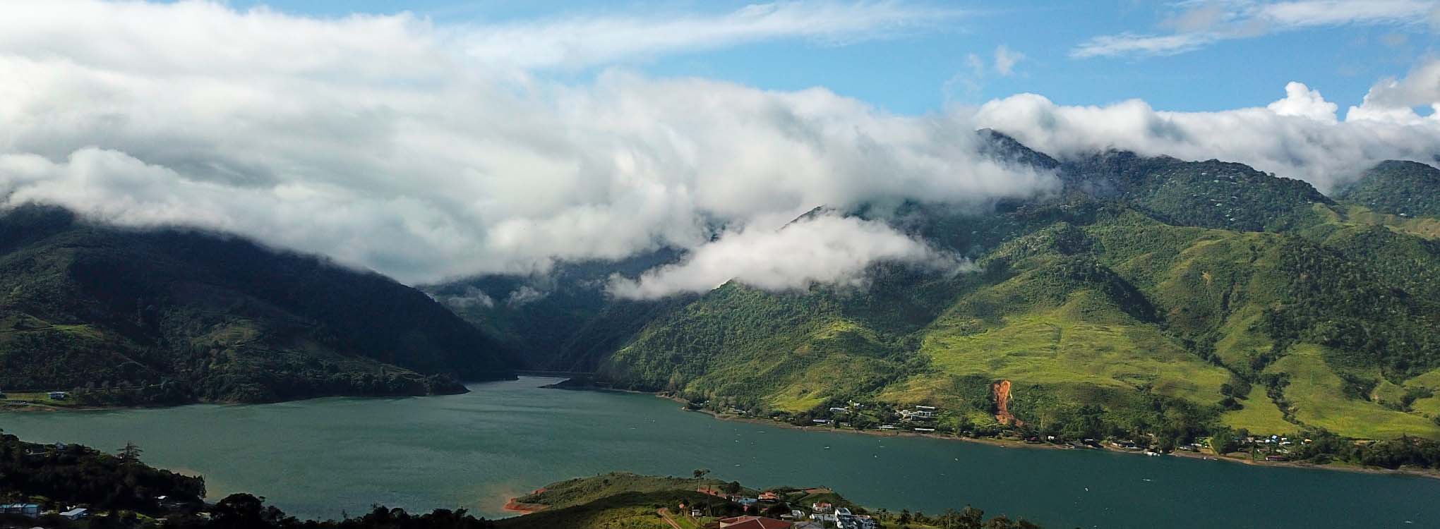 Paisaje montañoso con un lago rodeado de vegetación.