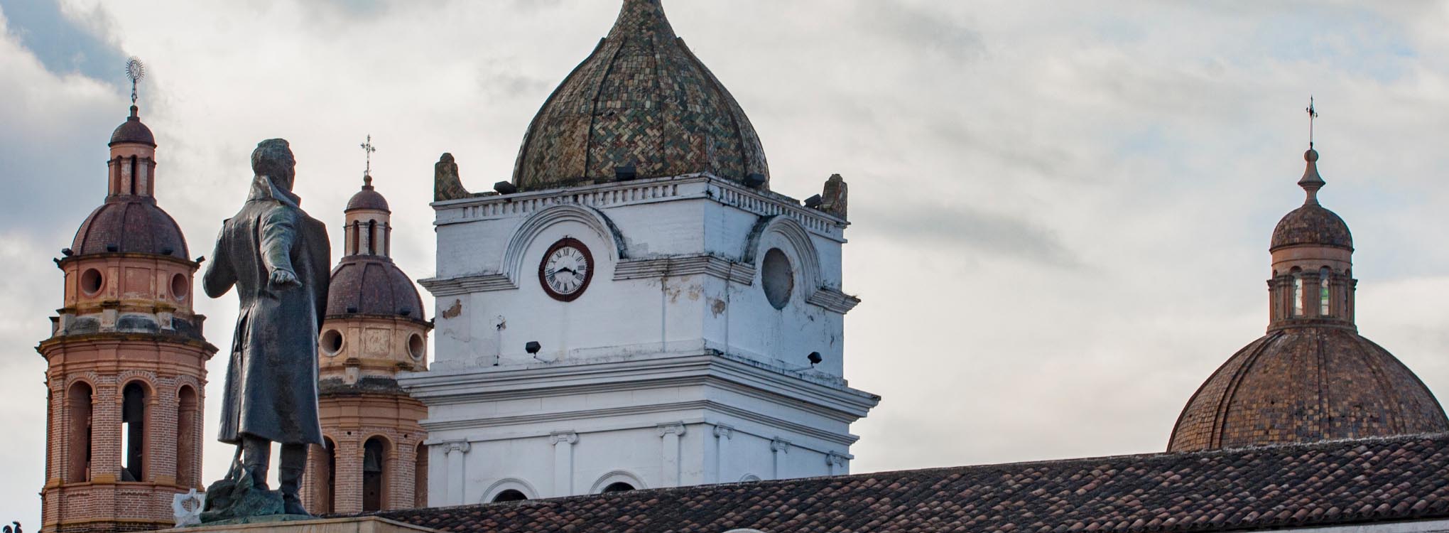 Primer plano de la catedral de Pasto, Nariño, con sus distintivas cúpulas y una estatua histórica.