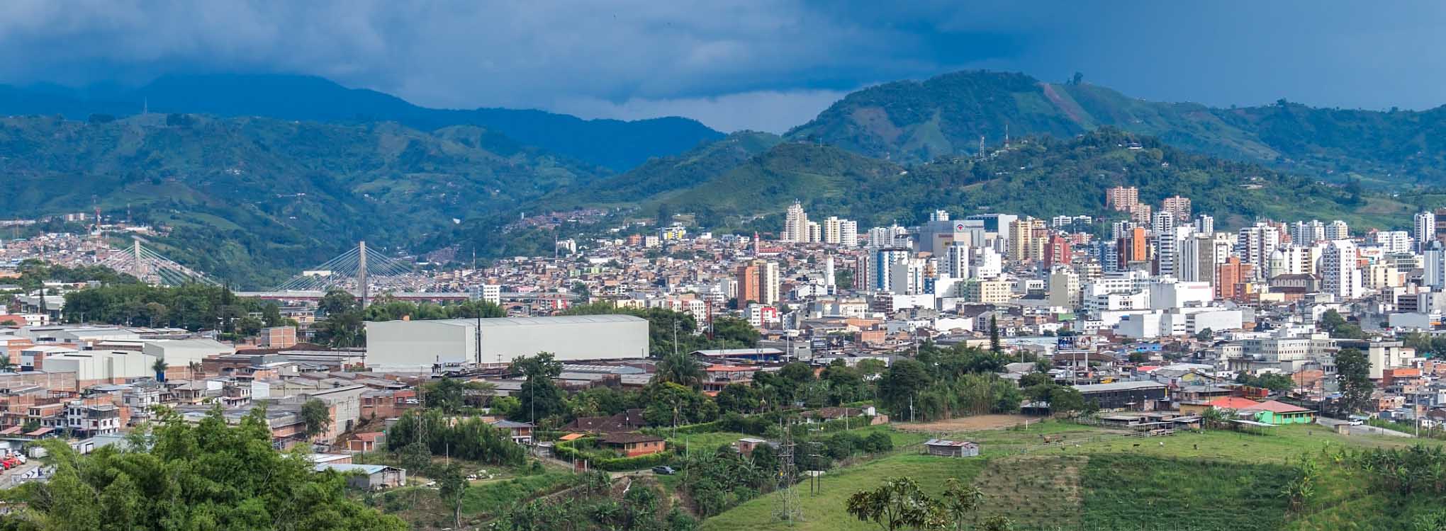 Vista panorámica de Pereira con sus edificios urbanos rodeados de montañas y plantaciones verdes.