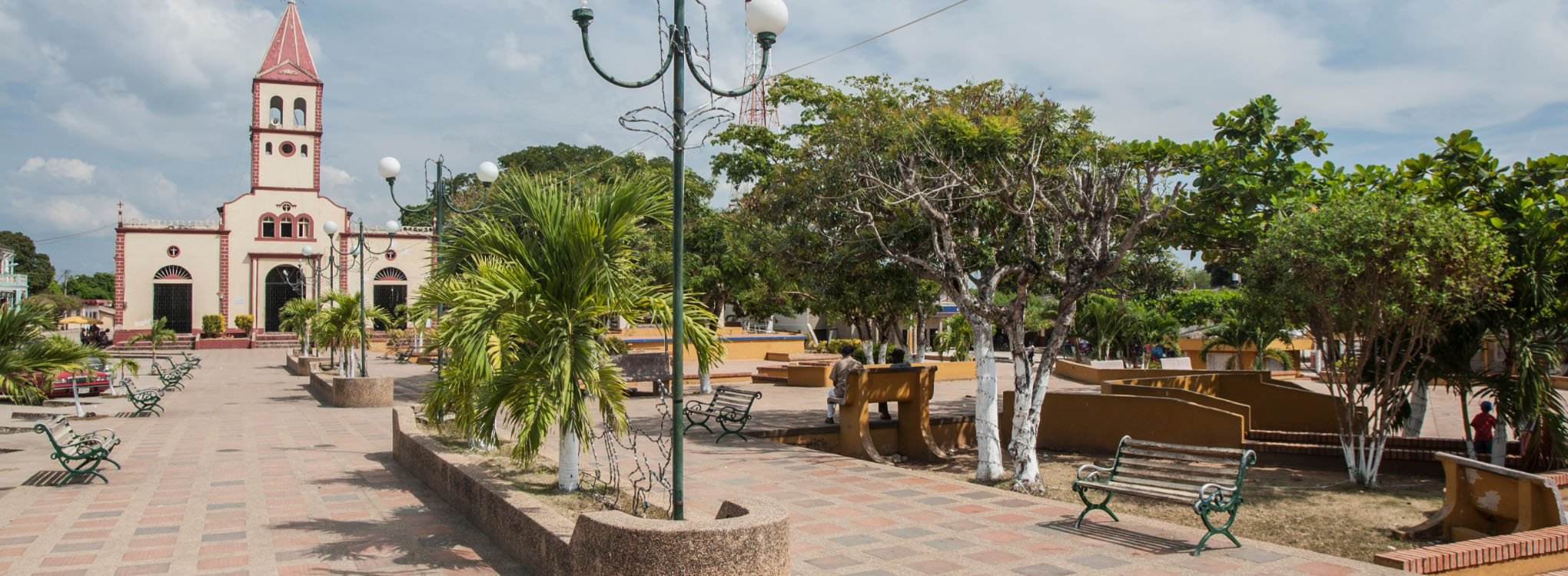 Plaza principal de Sincelejo con árboles, bancos y faroles, destacando una iglesia de fachada