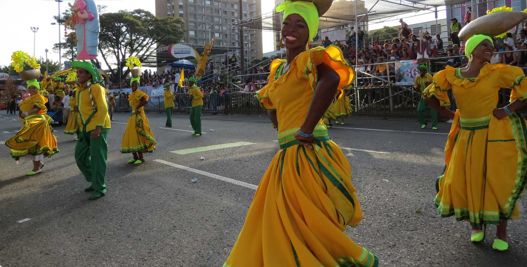 Desfile cultural con participantes vestidos con trajes tradicionales amarillos y verdes.