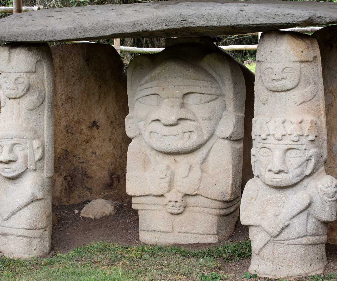 Grupo de estatuas precolombinas talladas en piedra, con rostros estilizados y ornamentación.