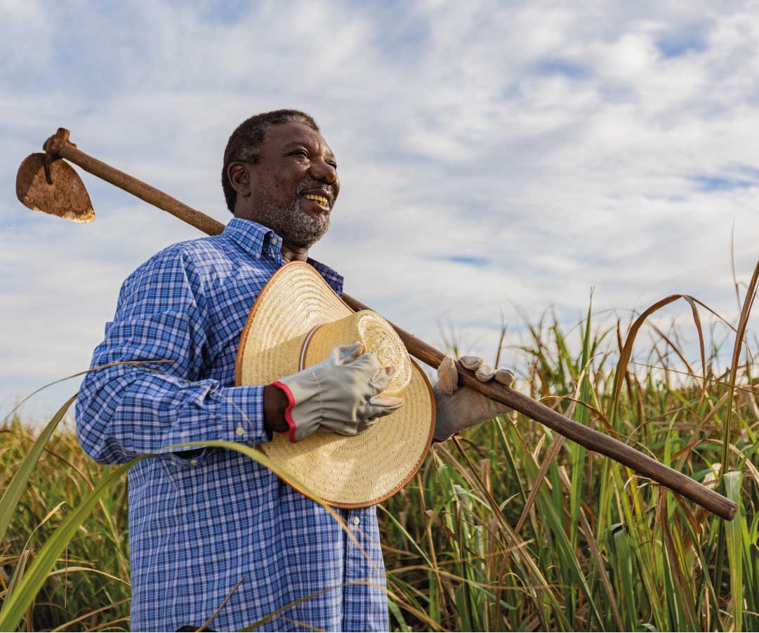 Hombre agricultor sonriendo, sosteniendo una herramienta de cultivo.