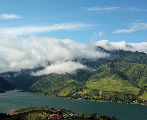 Paisaje montañoso con un lago rodeado de vegetación.