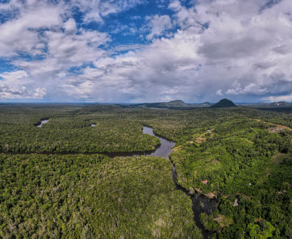 Vista aérea de la selva amazónica con ríos serpenteantes, densa vegetación y colinas en el horizonte.