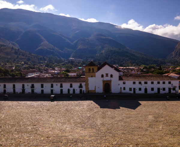 Plaza histórica con una iglesia colonial al fondo, rodeada de montañas en Boyacá.