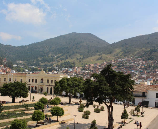 Plaza principal de una ciudad en Norte de Santander, rodeada de árboles, jardines y edificios.