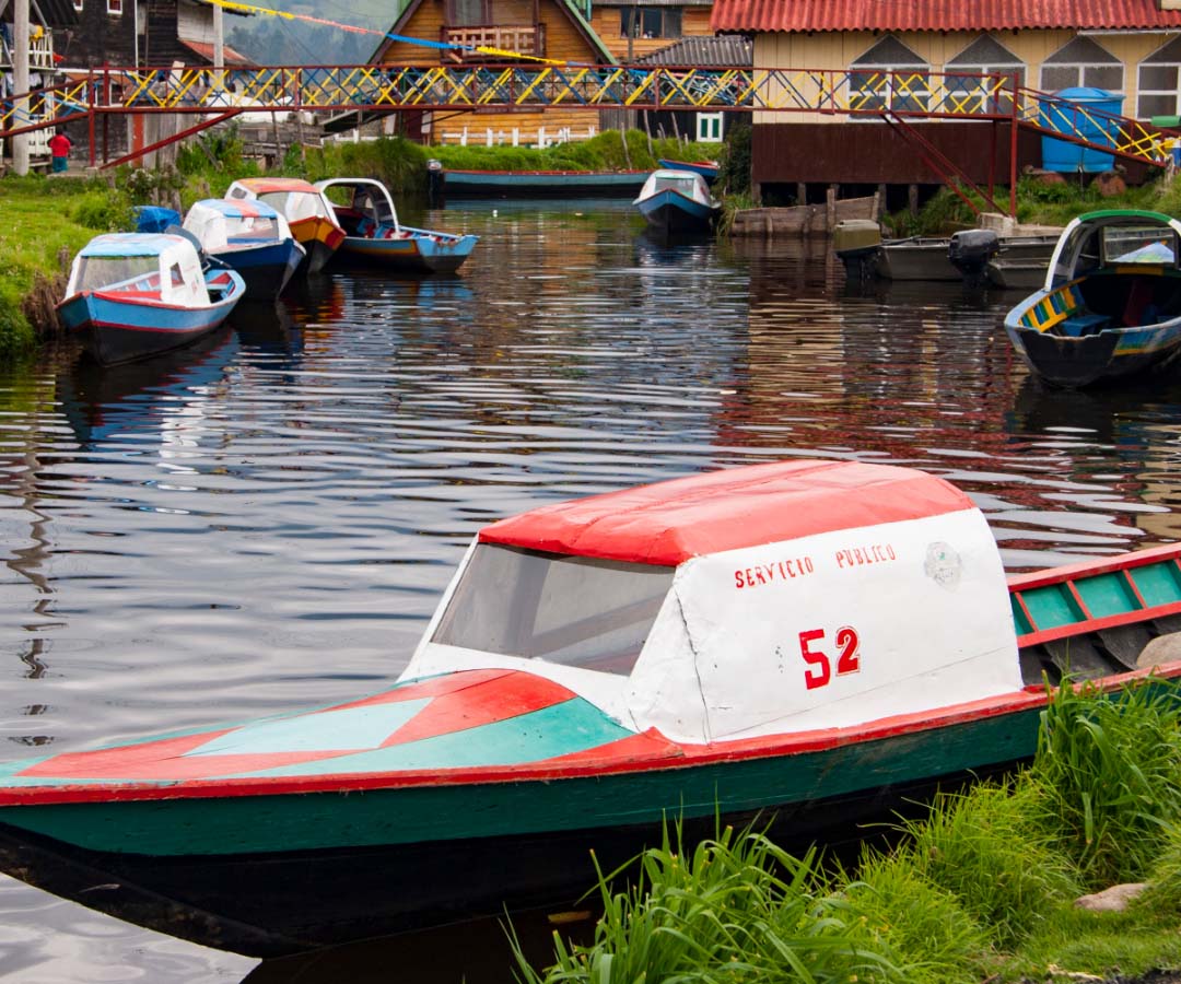 Pequeña embarcación de servicio público número 52 en blanco, rojo y verde amarrada junto a otras lanchas en un canal.