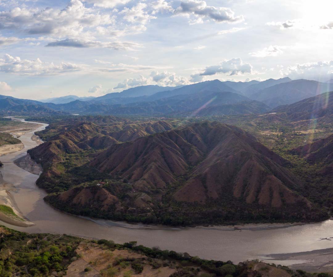 Vista aérea de un río serpenteante que forma un meandro pronunciado entre montañas.