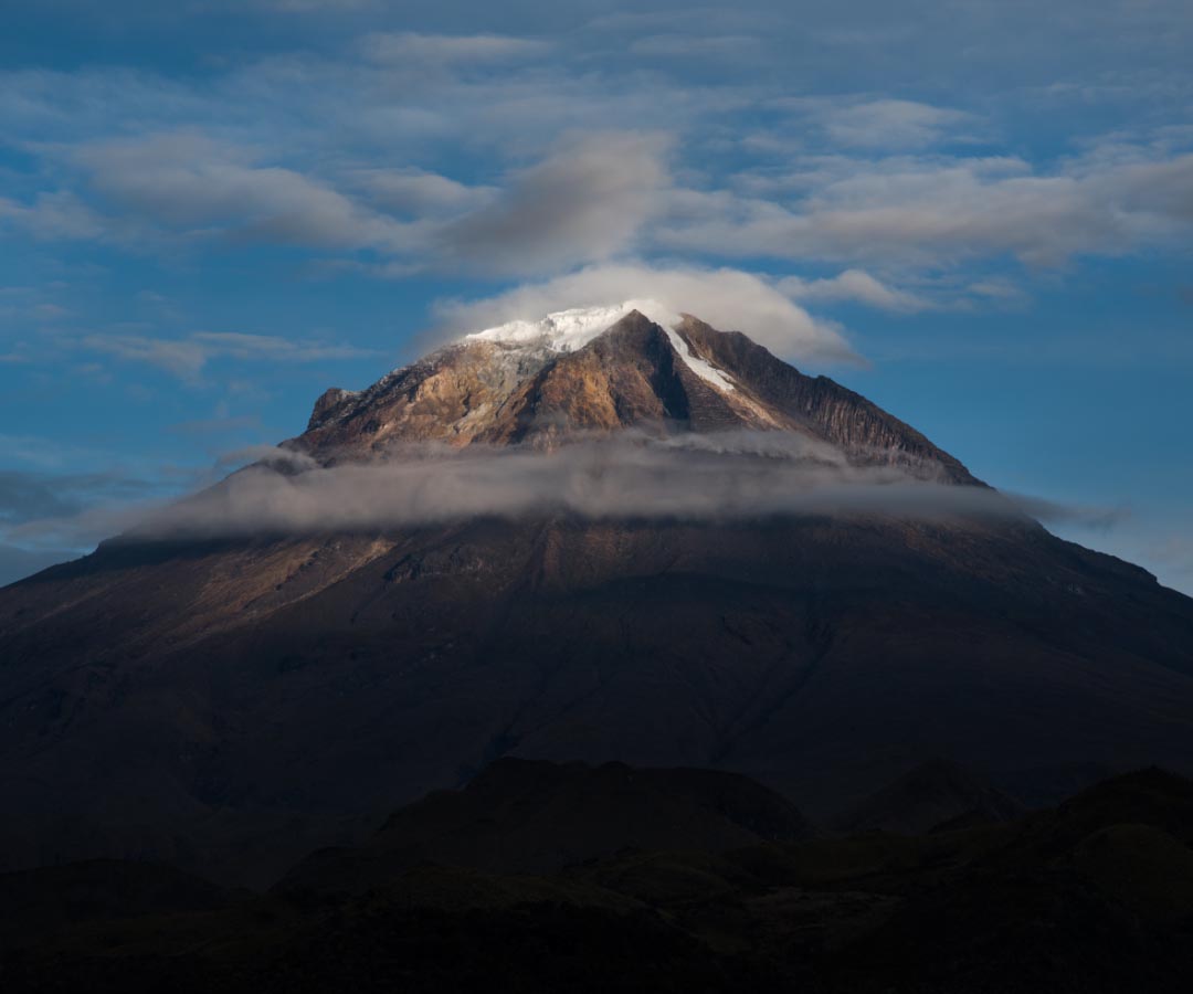 Vista del majestuoso volcán cubierto de nieve y rodeado de nubes bajas.