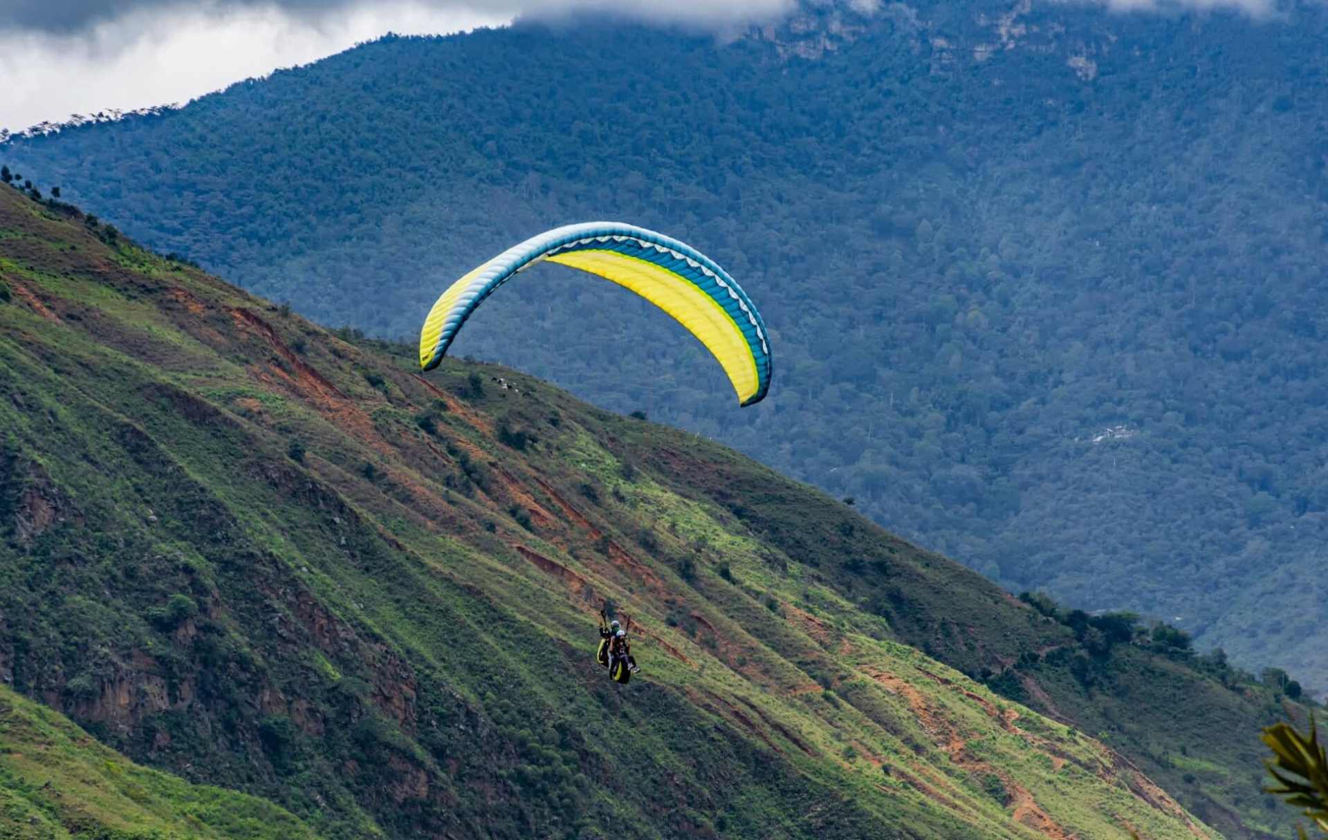 Persona practicando parapente sobre montañas verdes en Bucaramanga.