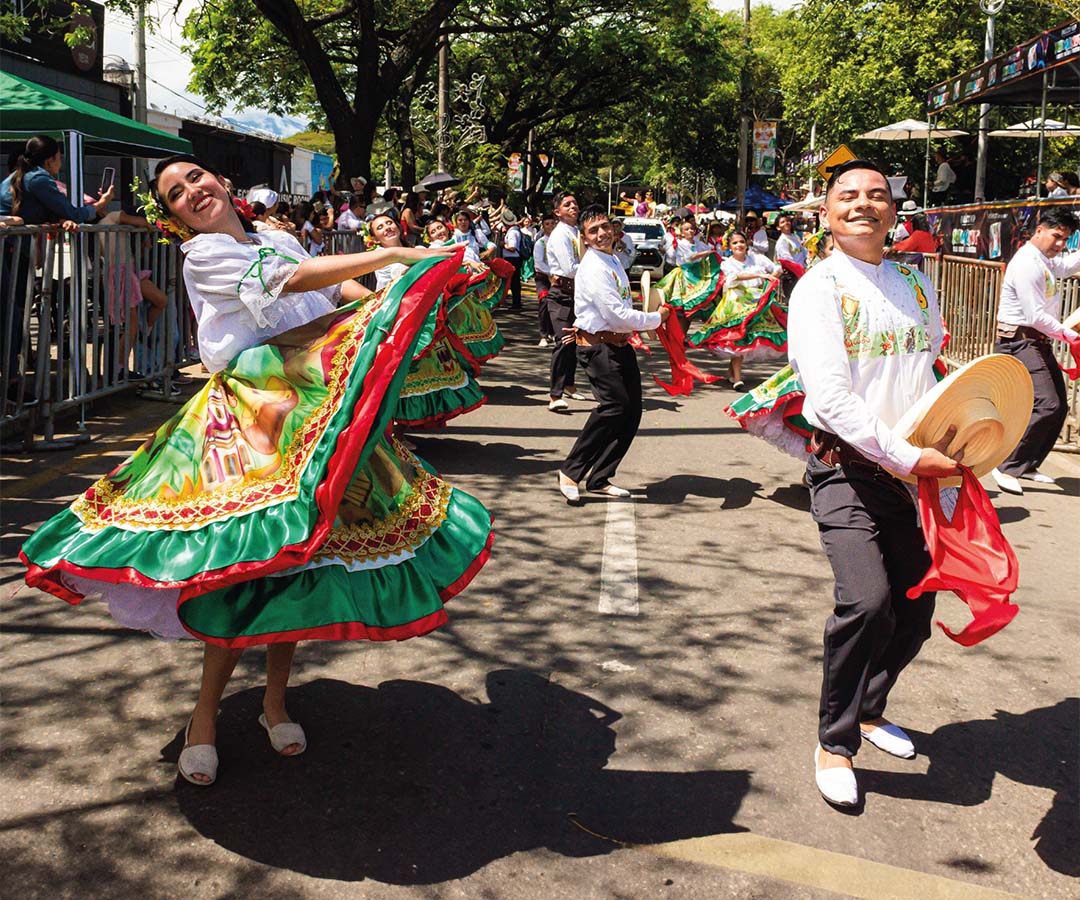 Grupo de bailarines en Neiva durante un desfile folclórico, luciendo trajes tradicionales coloridos mientras realizan pasos típicos.