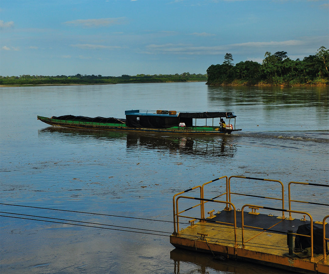 Barco navegando por un río con un muelle en primer plano.