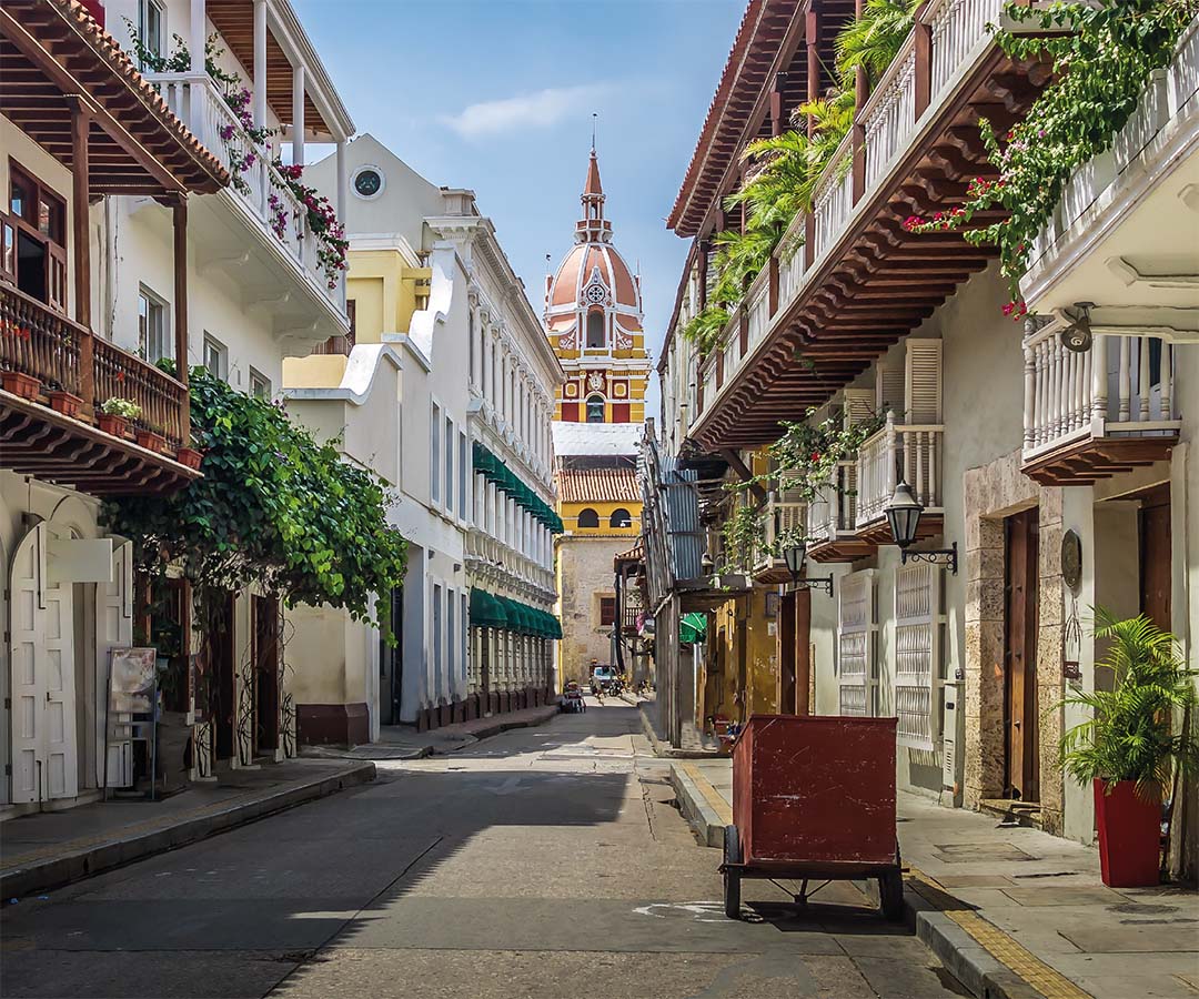 Calle colonial en Cartagena, Colombia, con casas coloridas de balcones adornados.