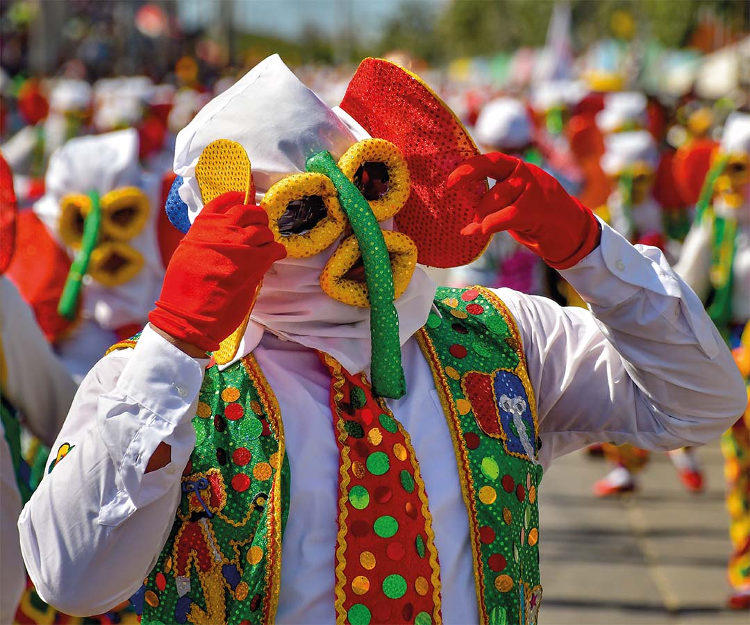 Persona disfrazada con máscara colorida y vestimenta tradicional del Carnaval de Barranquilla.