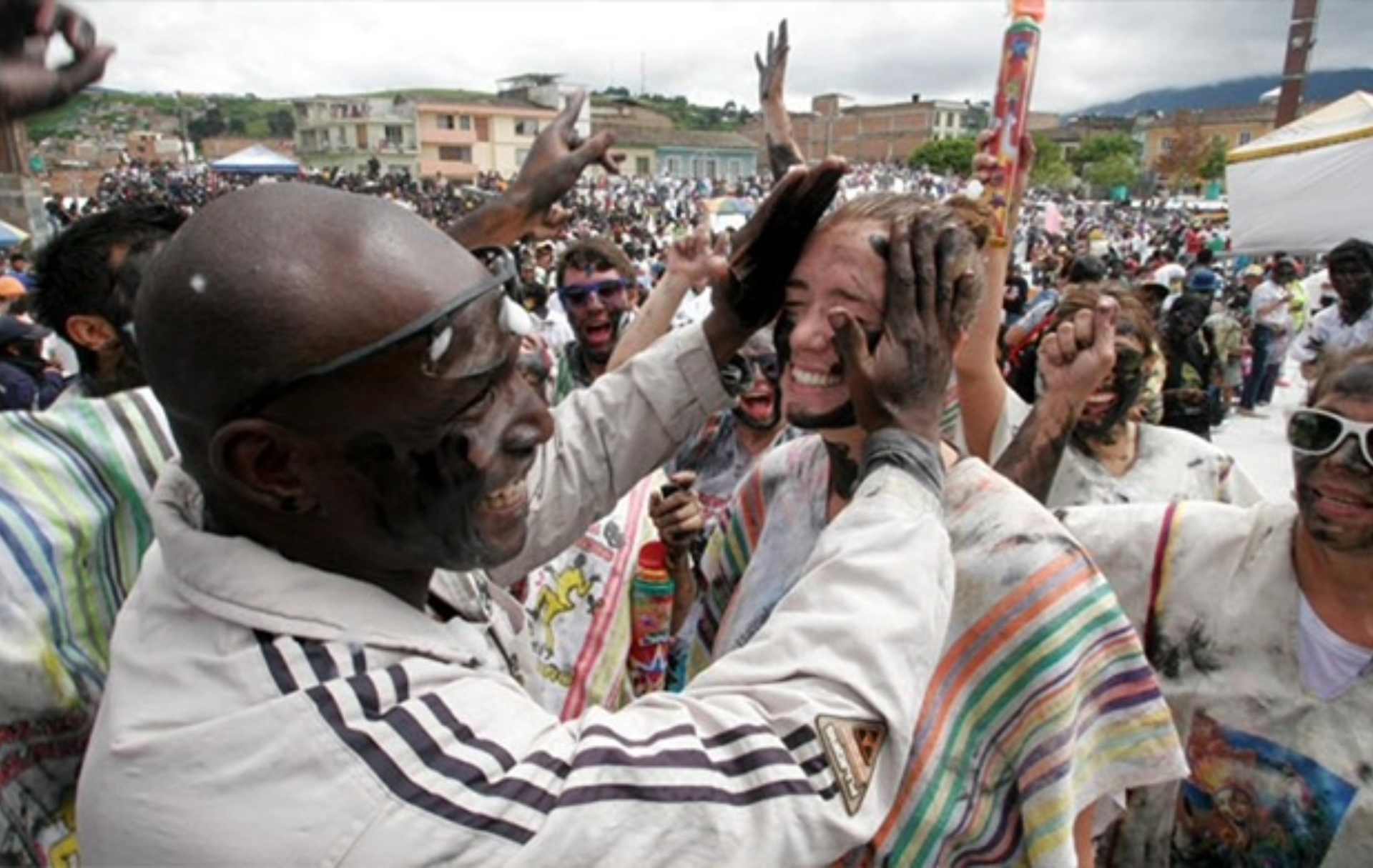 Personas celebrando el Carnaval de Negros y Blancos, pintándose mutuamente