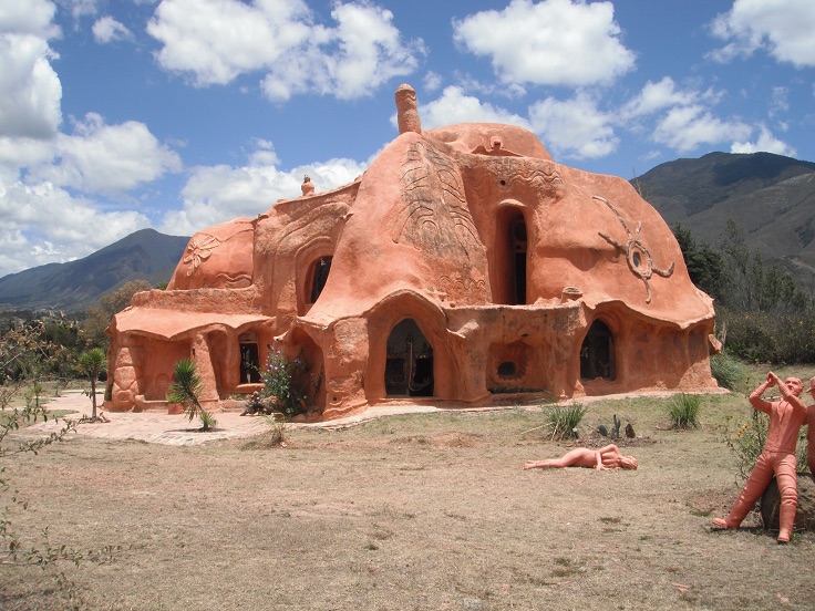 Casa de tierra con forma orgánica y esculturas.