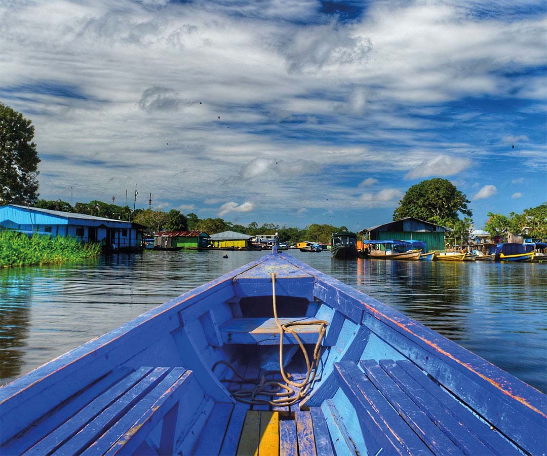 Bote navegando entre casas flotantes.