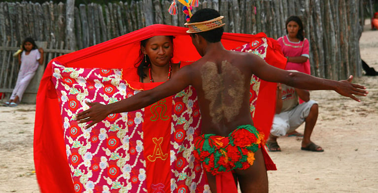 Pareja de indígenas realizando una danza tradicional con vestimenta colorida