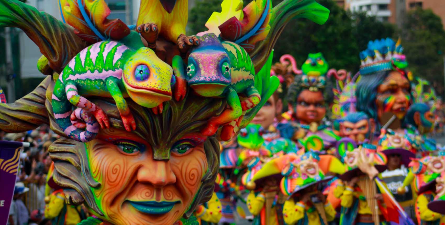 Carroza colorida con figuras artísticas de camaleones y rostros pintados en un desfile cultural.