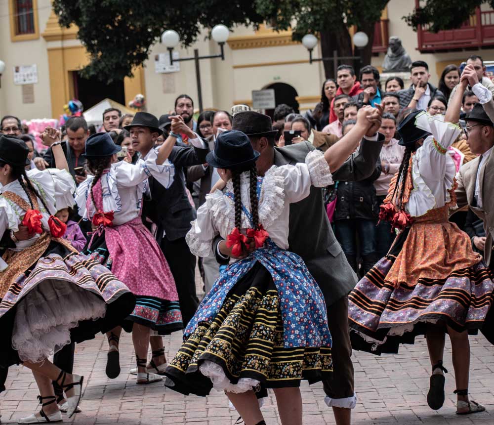 Grupo de bailarines folklóricos en pareja, vestidos con trajes típicos coloridos y sombreros.