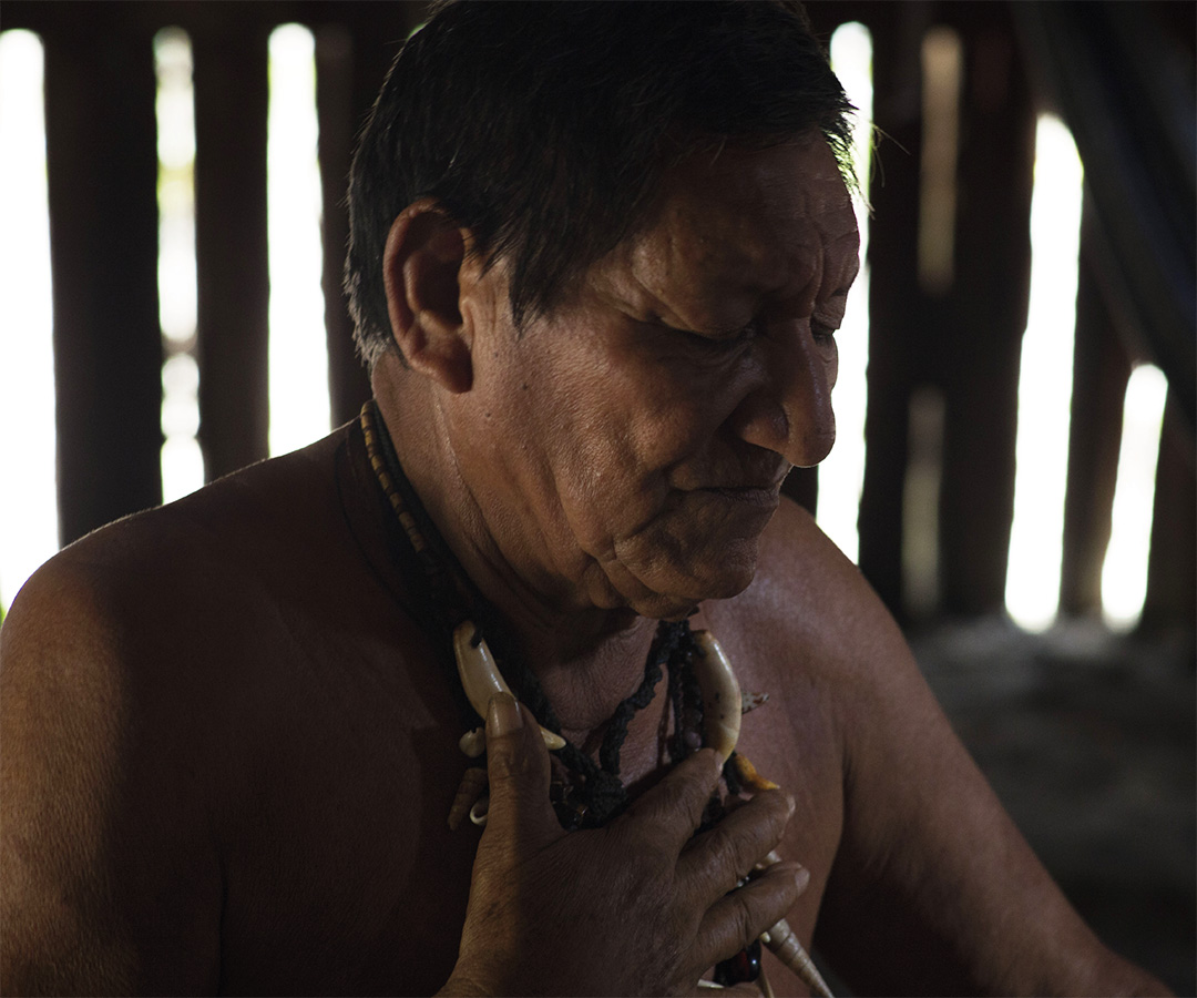 Hombre indígena mayor dentro de una vivienda tradicional.