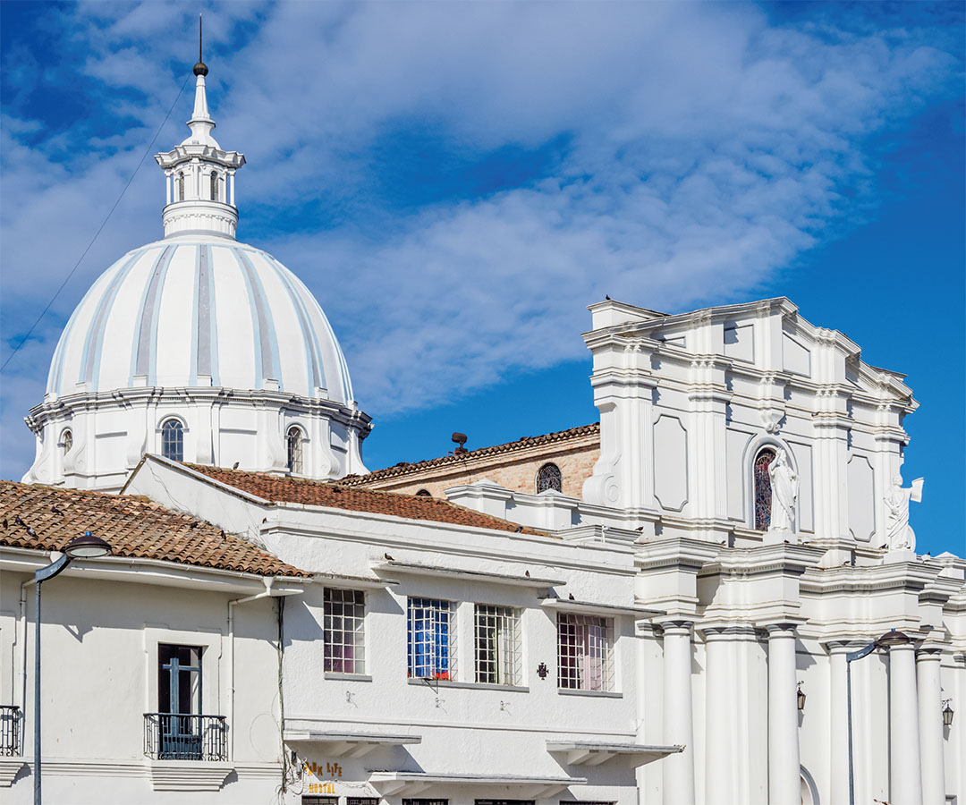 Cúpula de una iglesia colonial en Popayán, con arquitectura blanca detallada, techos de tejas y un cielo azul despejado