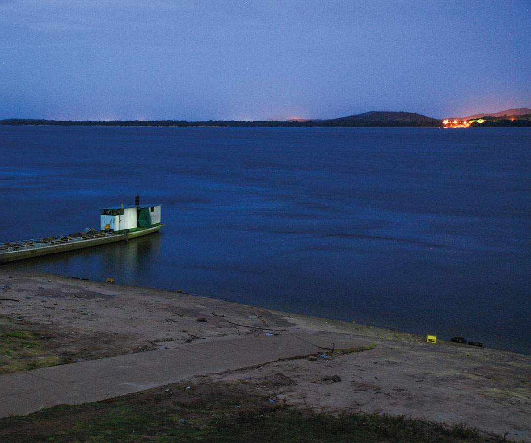 Lago tranquilo al amanecer con la ciudad al fondo.