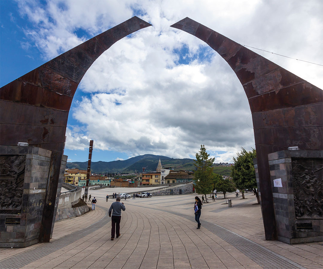 Arco del Monumento a la Resistencia en Nariño, con vistas a la plaza central, rodeado de montañas y un cielo parcialmente nublado.