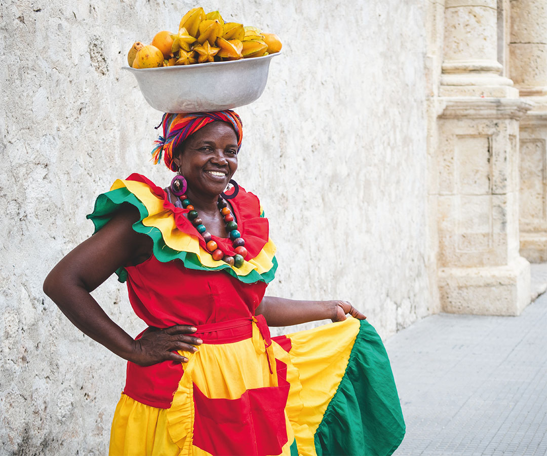 Mujer palenquera en Cartagena, Colombia, vistiendo un colorido traje tradicional.