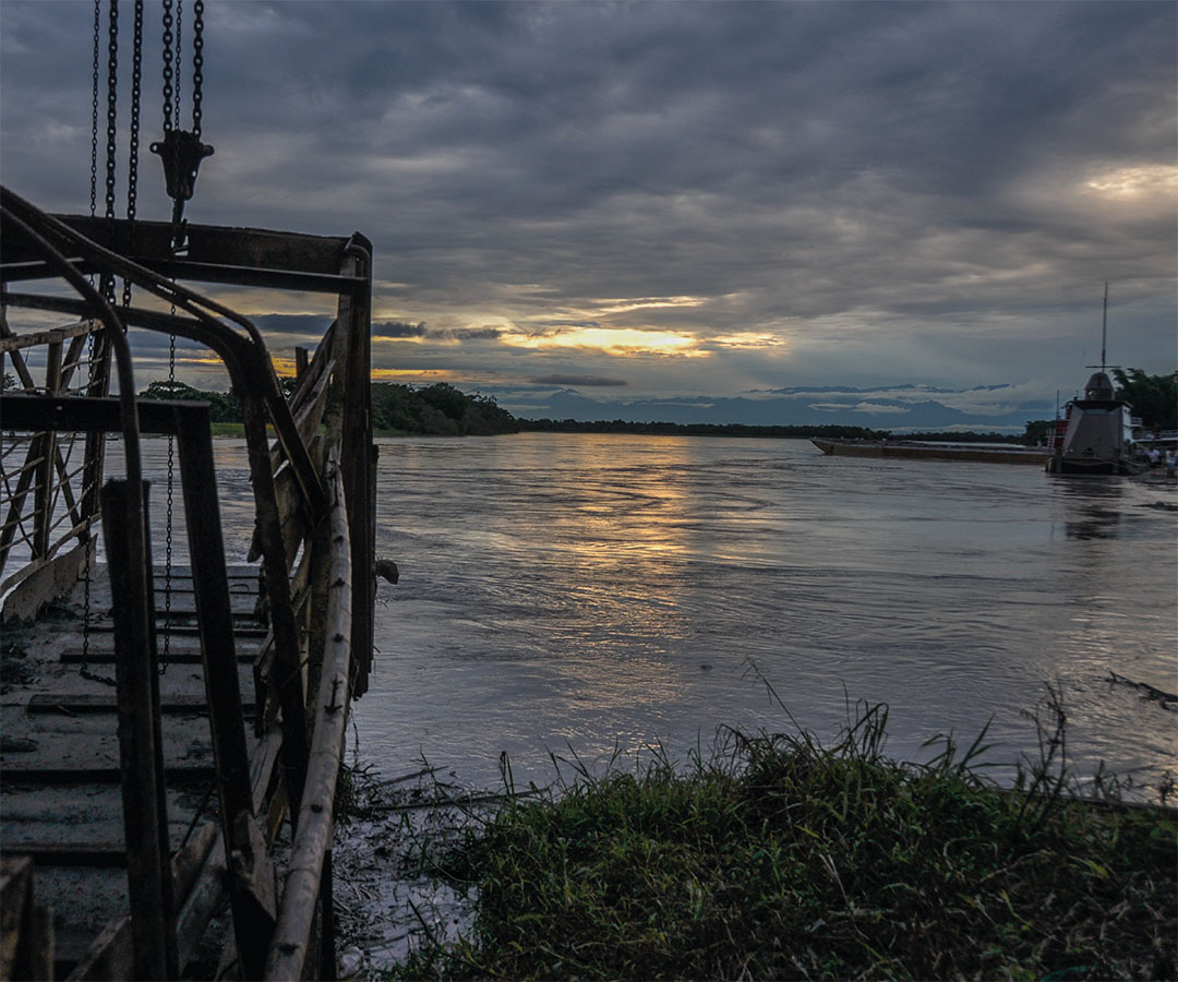 Paisaje fluvial al atardecer con un barco anclado.