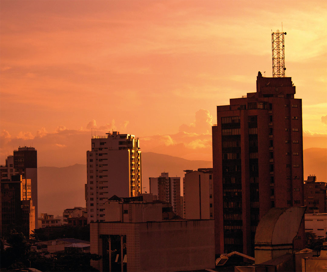 Paisaje urbano de Bucaramanga, Santander, Colombia, al atardecer, con edificios iluminados por tonos anaranjados.