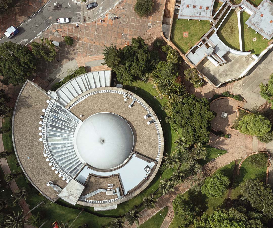 Vista aérea del Planetario de Bogotá, mostrando su estructura moderna rodeada de áreas verdes y caminos peatonales.