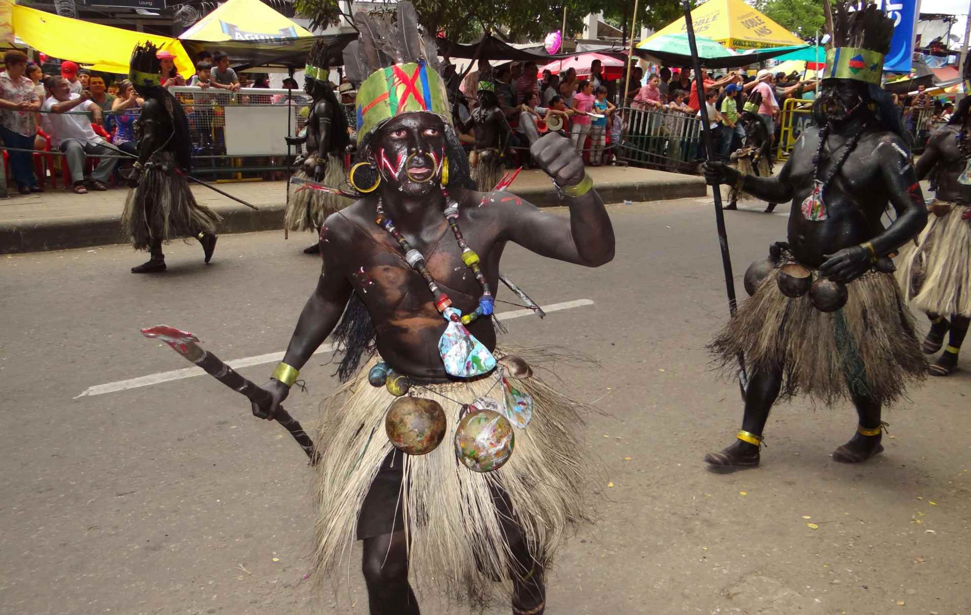 Hombre participando en un desfile cultural, vestido con un atuendo tradicional hecho de fibras naturales