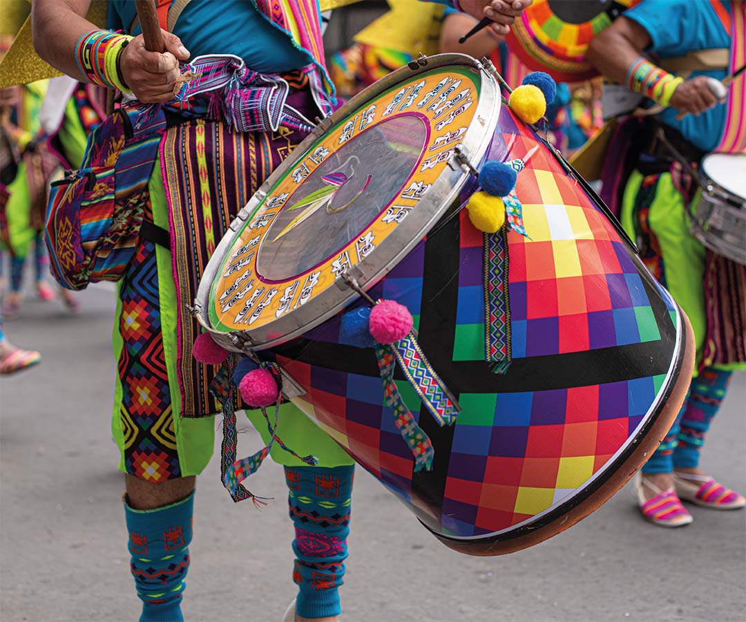 Detalle de un tambor decorado con colores vivos y patrones tradicionales, tocado durante un desfile cultural.