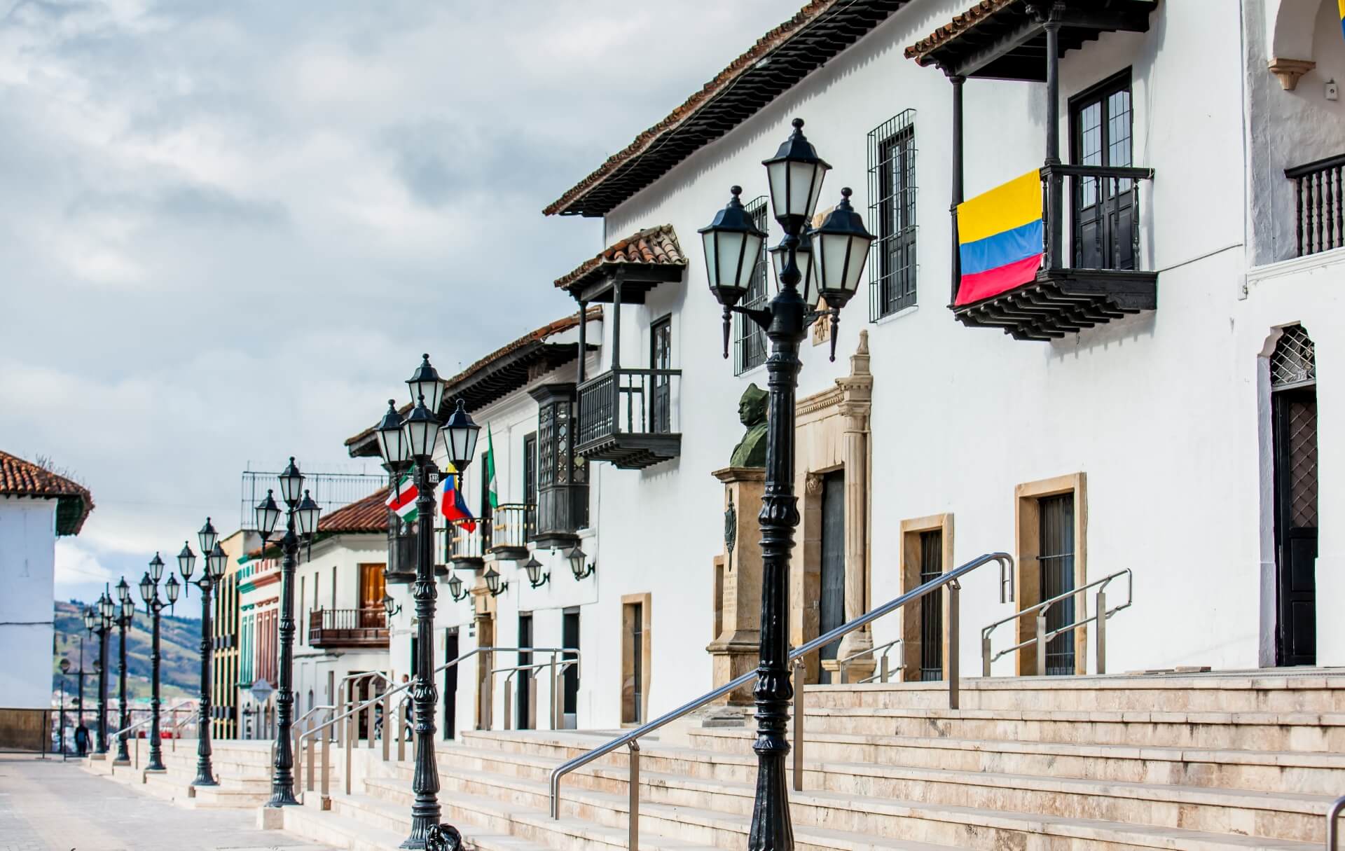 Calle colonial con edificios blancos y balcones.