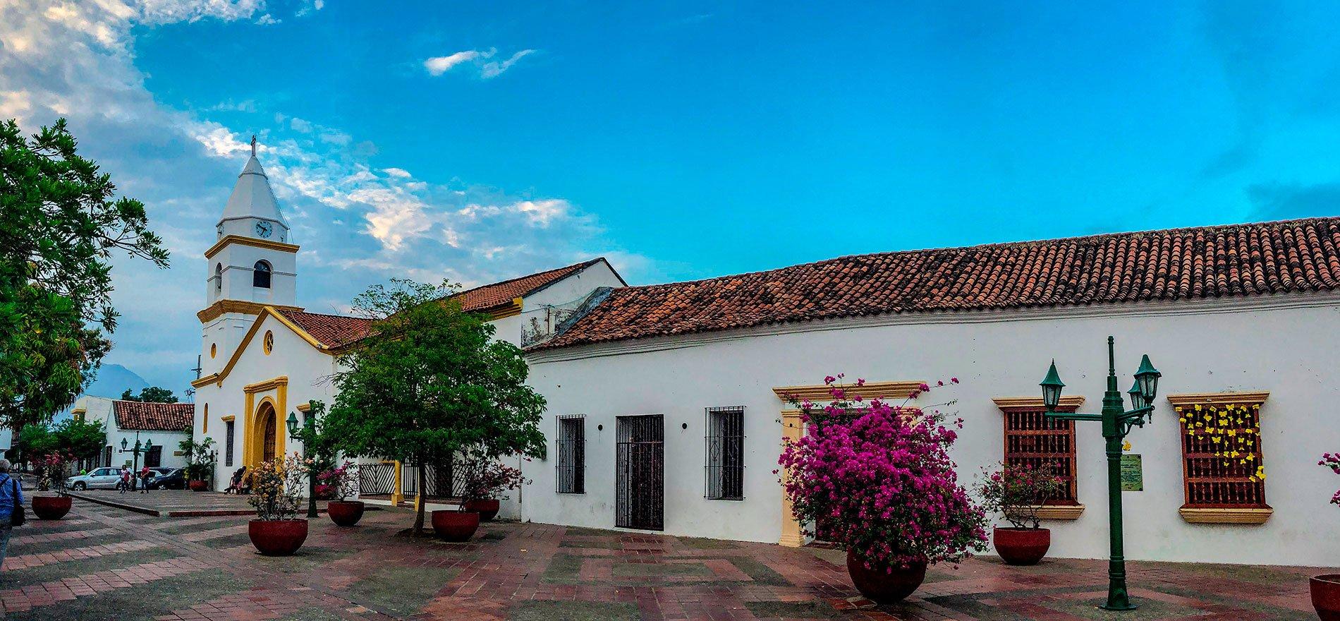 Plaza colonial con iglesia y casas blancas.