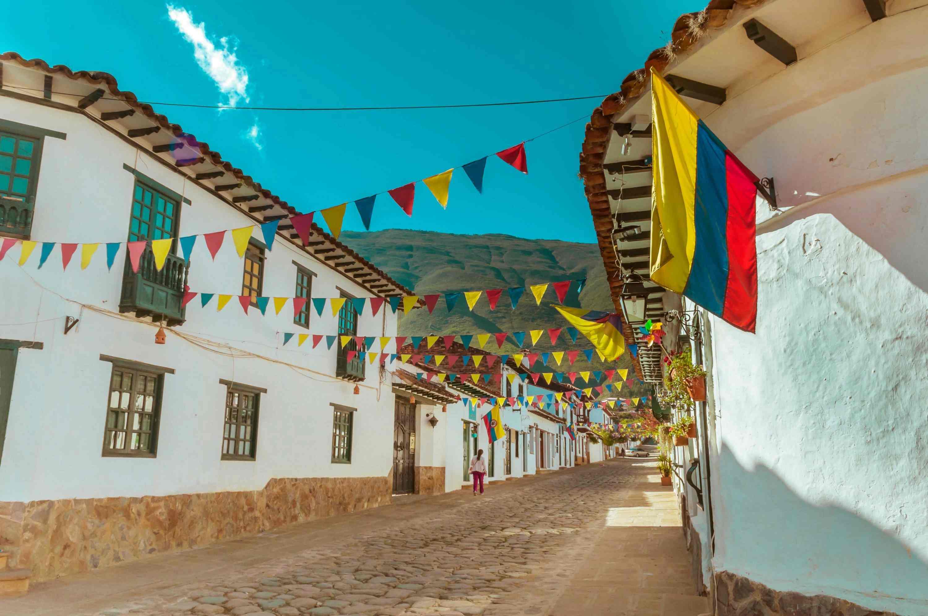 Calle colonial con casas blancas y banderas.