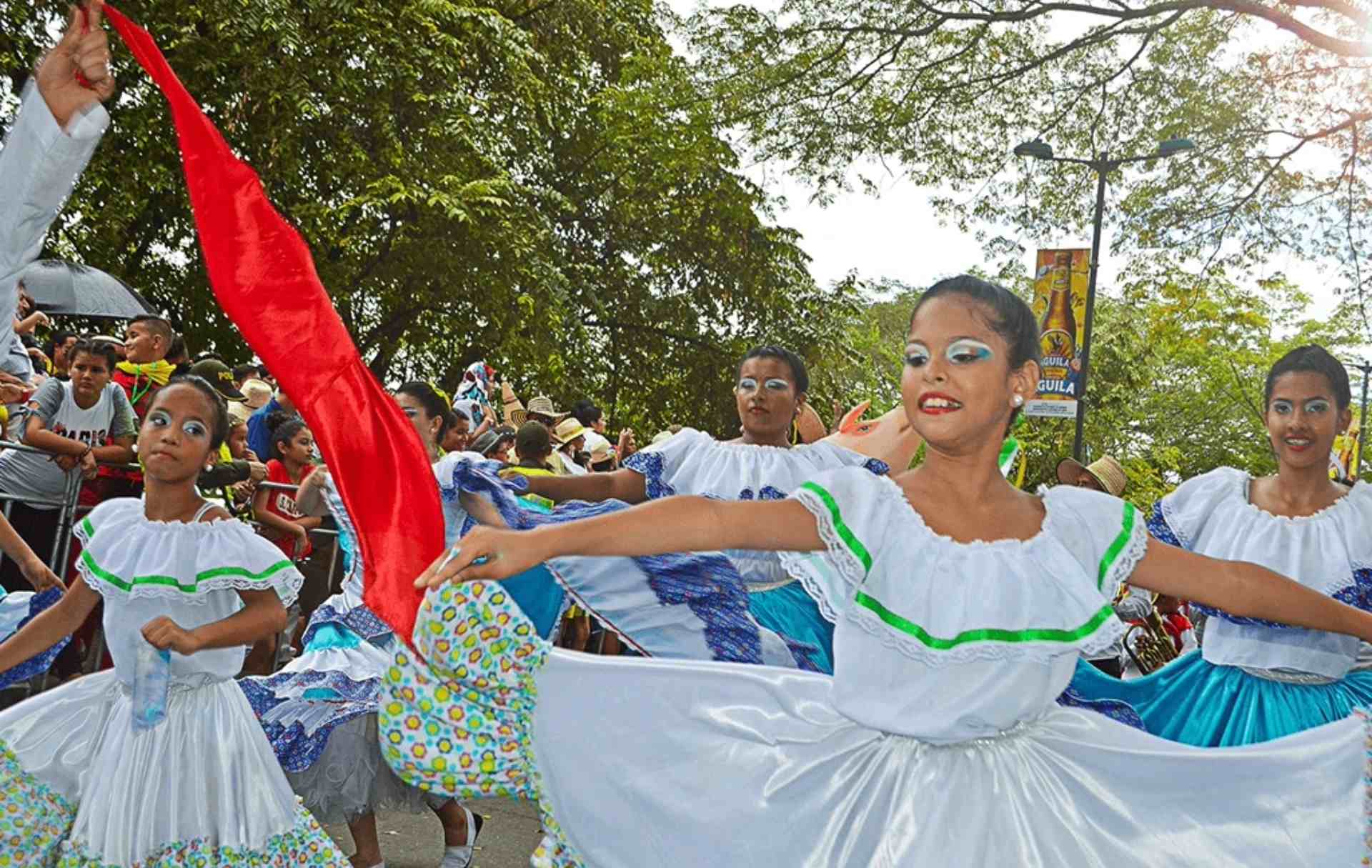 Niñas con trajes típicos bailando durante un desfile cultural en Villavicencio, Colombia.