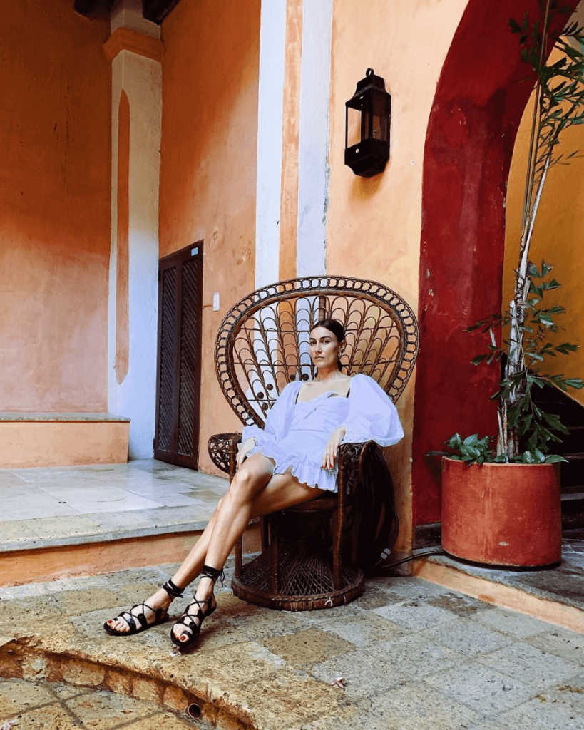 fotografía de Giorgia Tordini en una silla con un vestido morado corto dentro de una casa color naranja, moda Colombia