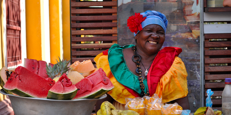 Palenquera en Cartagena, una de los representantes de la cultura colombiana – Palenquera sonriente en Cartagena vendiendo frutas colombianas | Marca País Colombia
