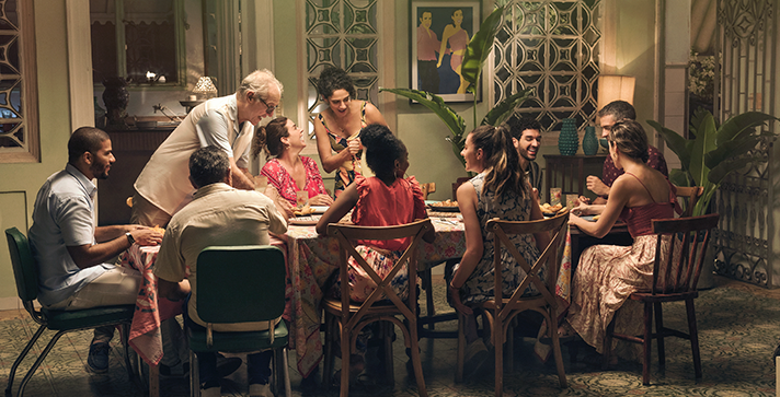 Fotografía de familia reunida en la mesa riendo y compartiendo juntos, familias colombianas 