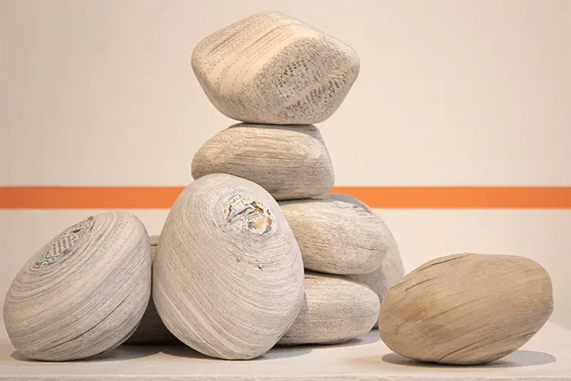 Escultura moderna de piedras apiladas envueltas en papel.